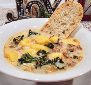 Creamy Italian soup filled with sausage, bacon, gnocchi, and kale in a ceramic farmhouse style soup bowl.